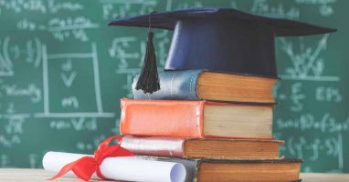 Graduation cap on books, degree scroll