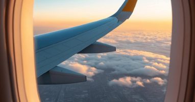 Airplane wing and clouds viewed through a cabin plane window